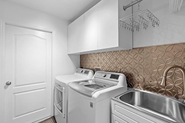 laundry area with washing machine and clothes dryer, cabinet space, and a sink