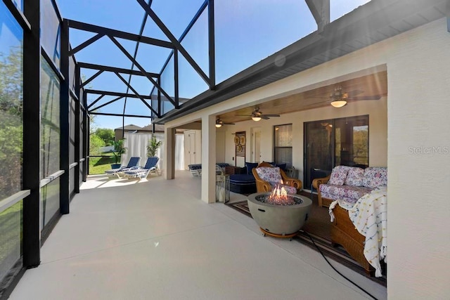 view of patio / terrace with glass enclosure, a ceiling fan, and an outdoor fire pit