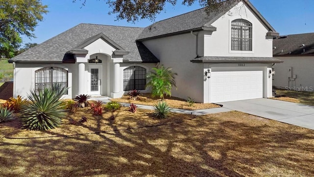 view of front facade featuring stucco siding, concrete driveway, a garage, and roof with shingles