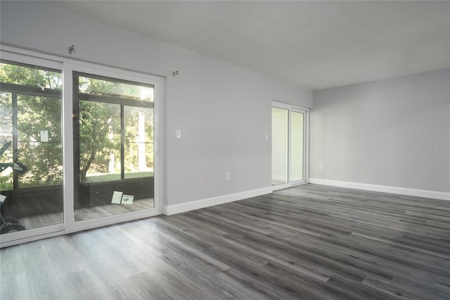 spare room with baseboards and dark wood-style flooring