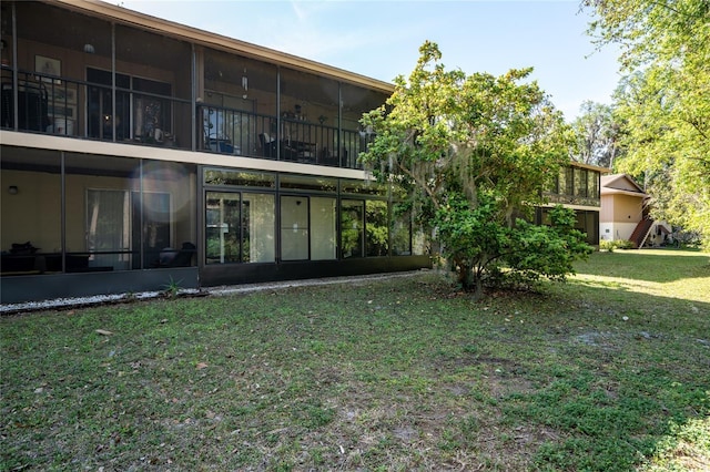 back of property with a lawn and a sunroom