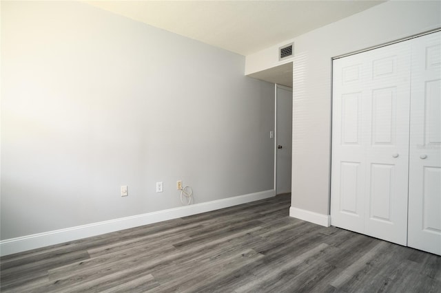 unfurnished bedroom with visible vents, baseboards, a closet, and wood finished floors