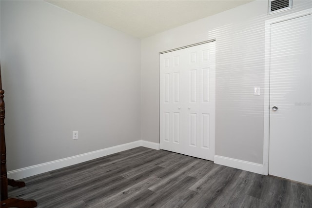 unfurnished bedroom featuring a closet, visible vents, baseboards, and dark wood-style flooring