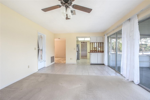 empty room with light tile patterned floors, light colored carpet, visible vents, and baseboards