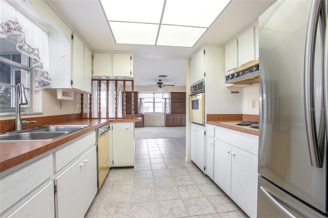 kitchen featuring under cabinet range hood, a sink, freestanding refrigerator, white oven, and dishwasher