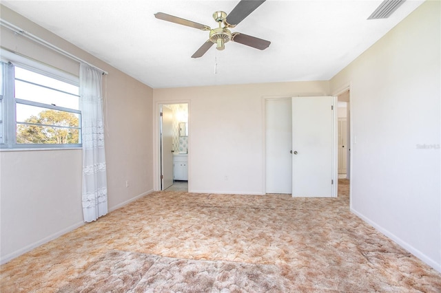 unfurnished bedroom featuring visible vents, baseboards, carpet floors, ensuite bathroom, and a ceiling fan