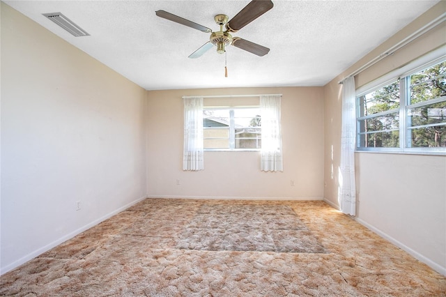 spare room featuring visible vents, a textured ceiling, carpet flooring, baseboards, and ceiling fan