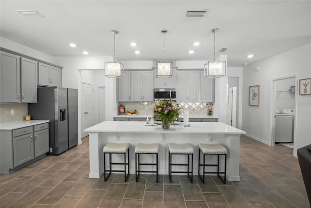 kitchen with visible vents, light countertops, gray cabinets, appliances with stainless steel finishes, and independent washer and dryer