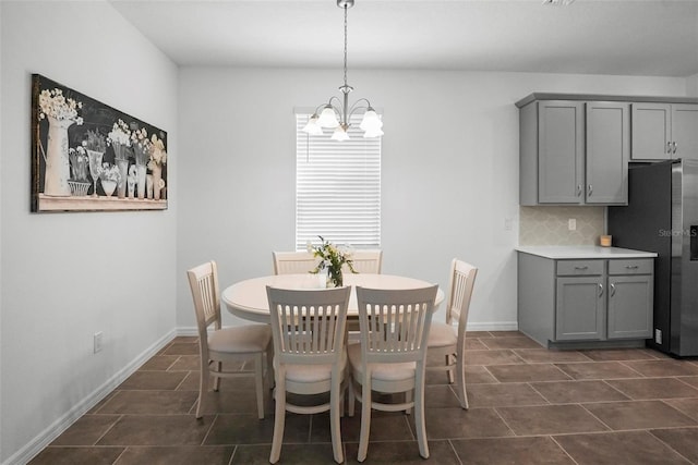 dining area featuring dark tile patterned floors, baseboards, and a chandelier