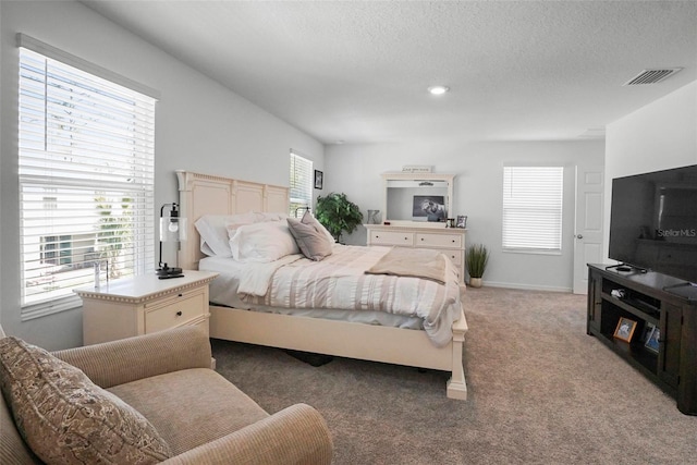 bedroom with visible vents, light carpet, a textured ceiling, and baseboards