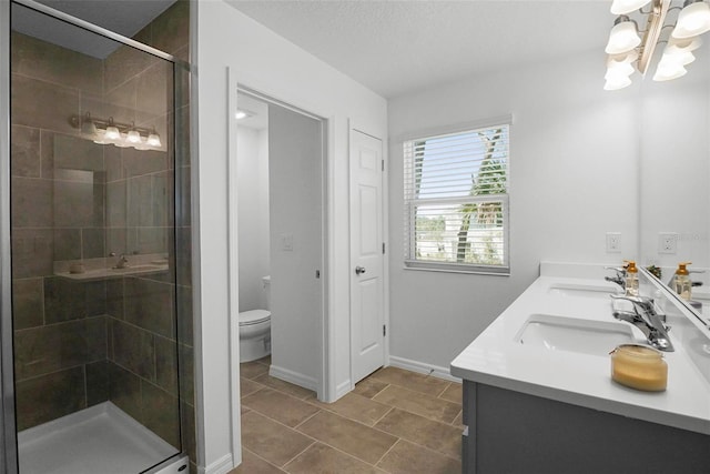 bathroom featuring a sink, toilet, double vanity, and a shower stall