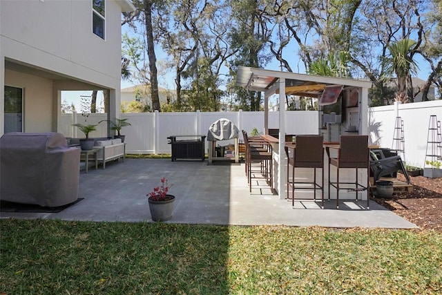 view of patio with a fenced backyard, outdoor dry bar, and grilling area