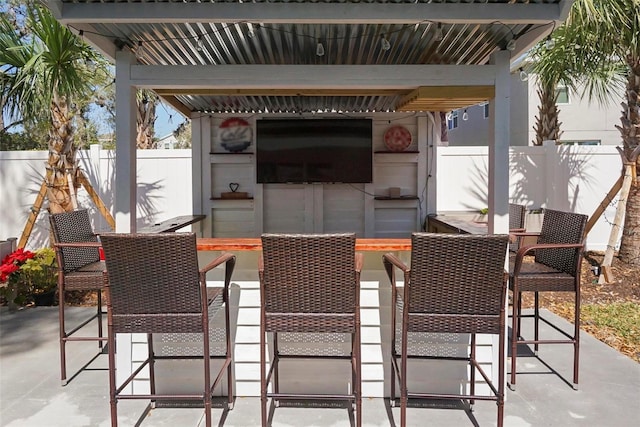 view of patio with outdoor dry bar and fence