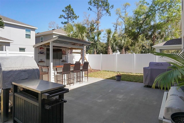 view of patio featuring outdoor dry bar, area for grilling, and a fenced backyard