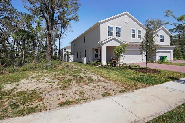 traditional-style house with stucco siding, an attached garage, and driveway