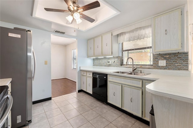 kitchen featuring visible vents, a tray ceiling, a sink, light countertops, and dishwasher