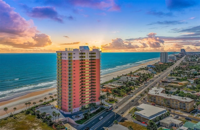 aerial view at dusk featuring a view of the beach, a view of city, and a water view