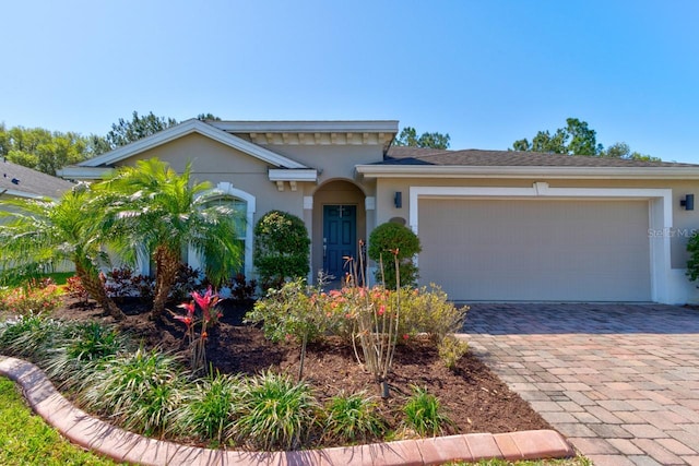 view of front facade featuring stucco siding, decorative driveway, and a garage