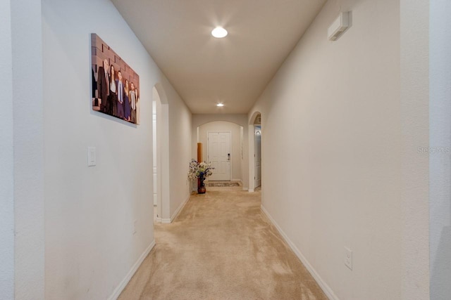 hall featuring recessed lighting, baseboards, arched walkways, and light carpet