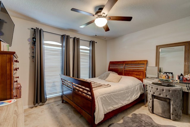 bedroom with light colored carpet, a ceiling fan, and a textured ceiling