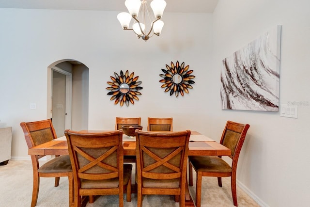 dining room with baseboards, arched walkways, a chandelier, and light carpet