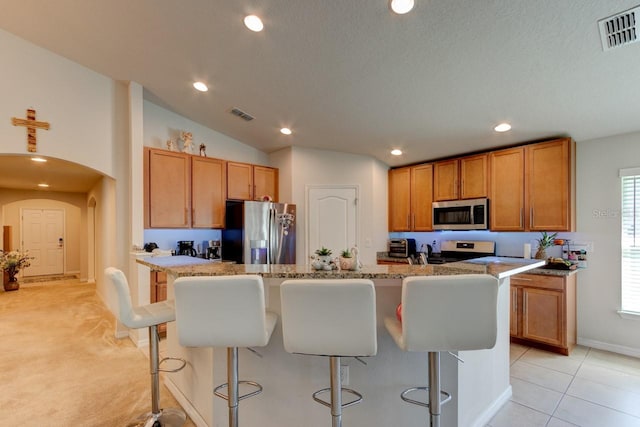 kitchen with stainless steel appliances, arched walkways, visible vents, and a kitchen breakfast bar