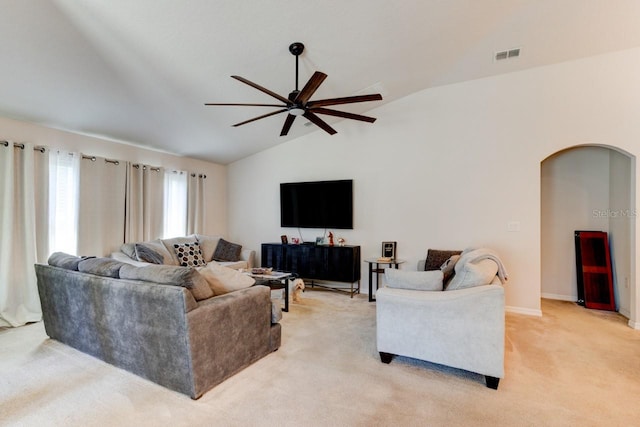 living area featuring visible vents, lofted ceiling, arched walkways, ceiling fan, and light carpet