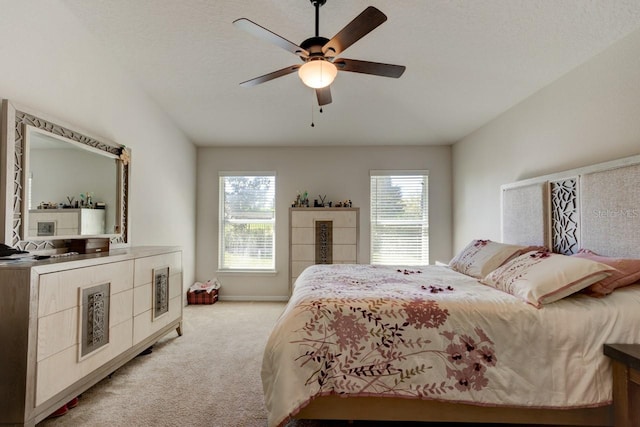 bedroom featuring multiple windows, light carpet, baseboards, and a ceiling fan