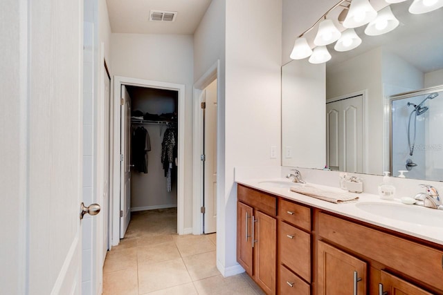 full bath with tile patterned flooring, a shower stall, double vanity, and a sink