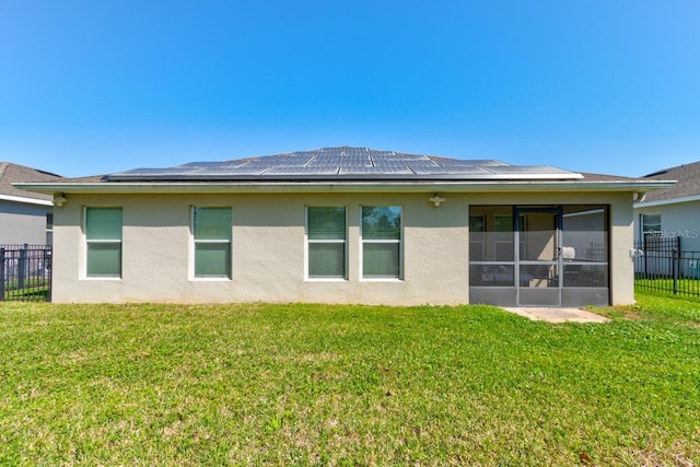 rear view of property with a lawn, fence, a sunroom, and stucco siding