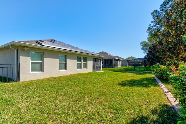 rear view of house featuring a fenced backyard, solar panels, a yard, and stucco siding