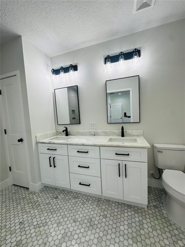 full bathroom with a sink, visible vents, toilet, and double vanity