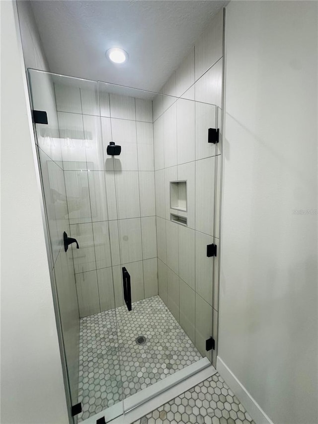 bathroom with tile patterned floors, a shower stall, and baseboards