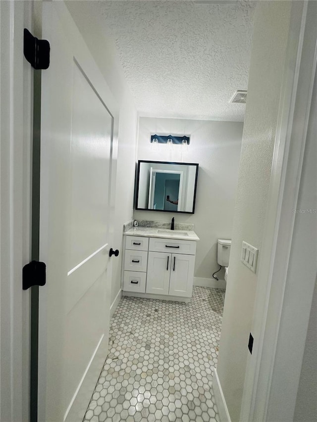 bathroom with visible vents, a textured ceiling, toilet, and vanity