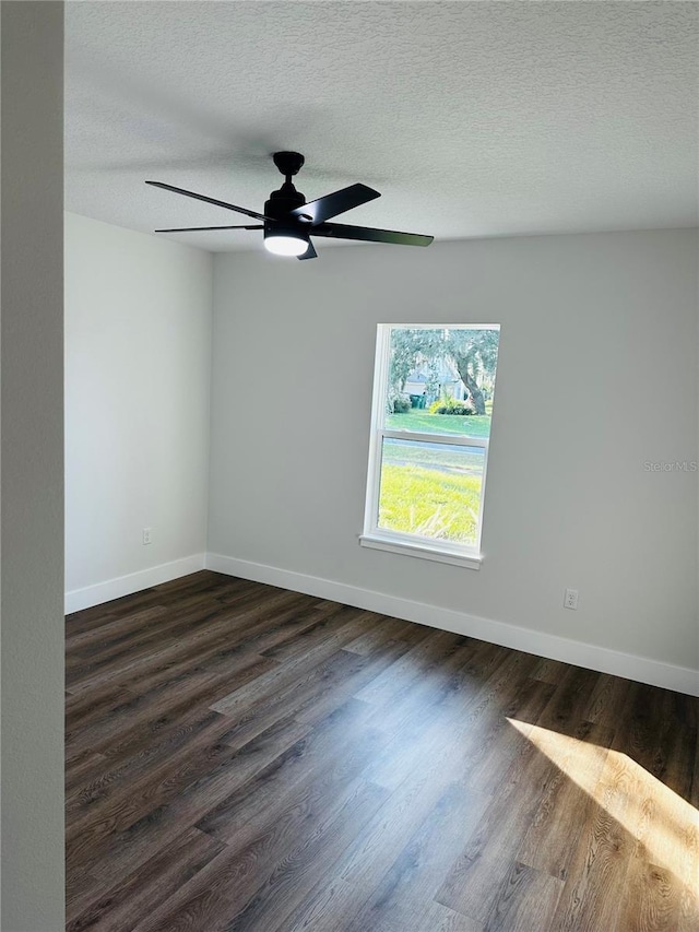 spare room featuring ceiling fan, baseboards, a textured ceiling, and dark wood-style floors