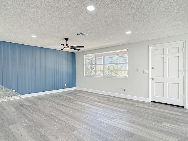 spare room featuring visible vents, wood finished floors, baseboards, and ceiling fan