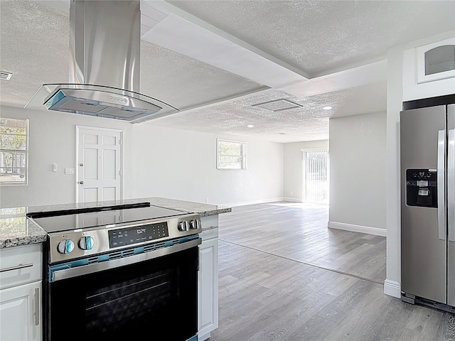 kitchen featuring light wood-style flooring, a textured ceiling, appliances with stainless steel finishes, and exhaust hood