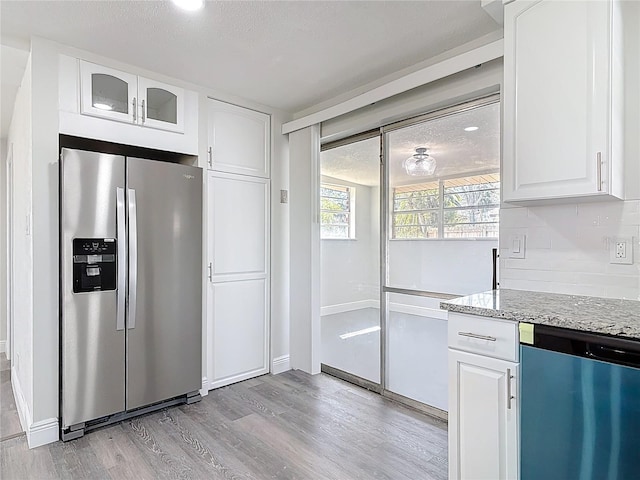 kitchen with light wood-style flooring, stainless steel refrigerator with ice dispenser, backsplash, light stone countertops, and dishwasher