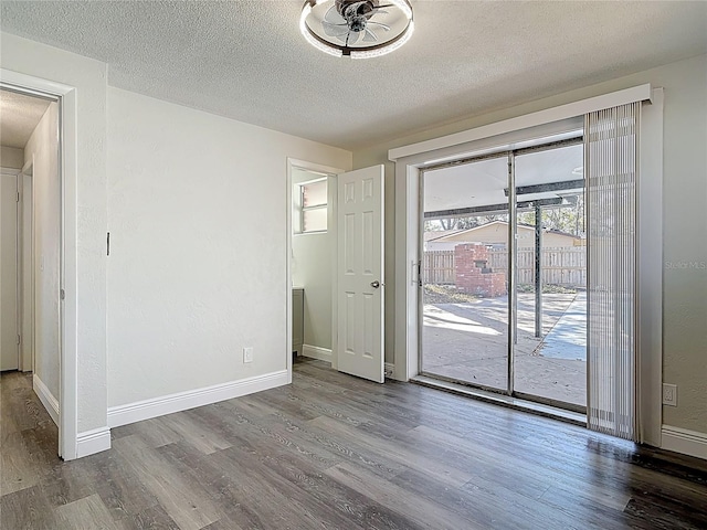 spare room with baseboards, a textured ceiling, and wood finished floors