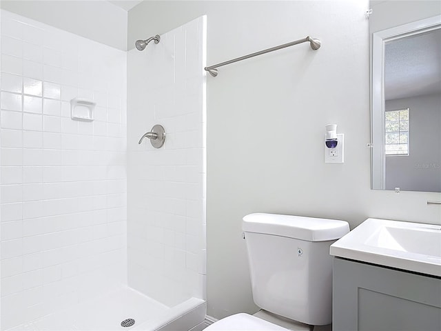 bathroom featuring vanity, toilet, and tiled shower