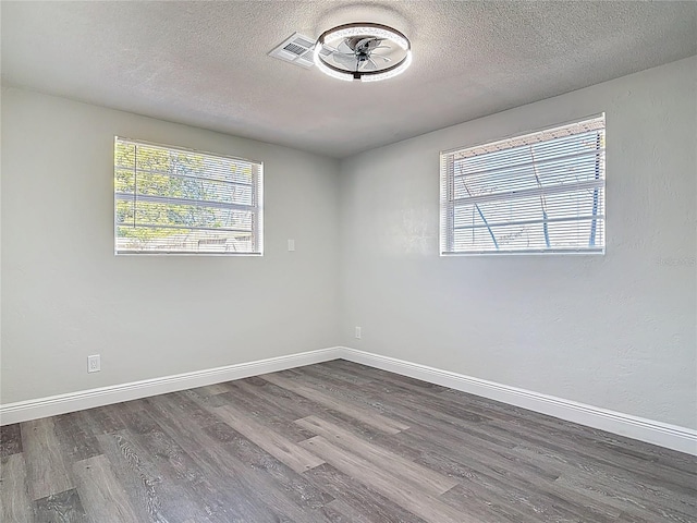 unfurnished room with wood finished floors, baseboards, and a textured ceiling