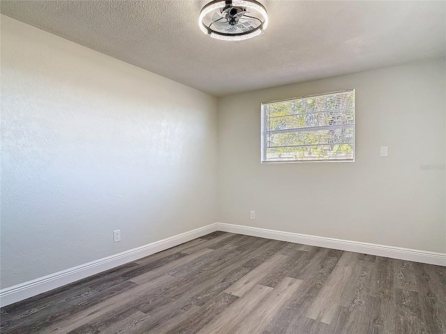 empty room featuring wood finished floors, baseboards, and a textured ceiling