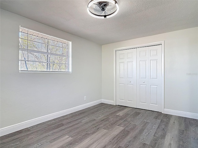 unfurnished bedroom featuring visible vents, baseboards, wood finished floors, a closet, and a textured ceiling