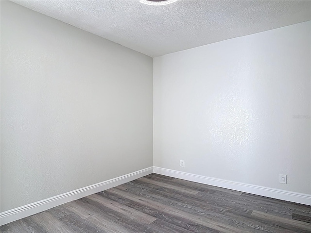 unfurnished room with baseboards, a textured ceiling, and dark wood-style flooring