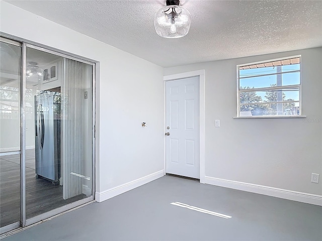 unfurnished room with baseboards, a textured ceiling, and finished concrete flooring