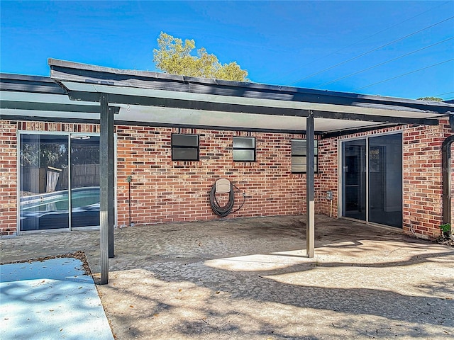 back of house with a patio, an attached carport, and brick siding