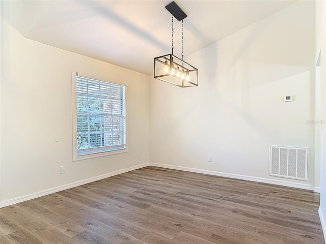 unfurnished room featuring visible vents, baseboards, and wood finished floors