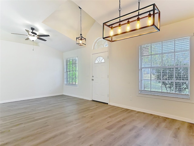 foyer featuring baseboards, lofted ceiling, wood finished floors, and a ceiling fan