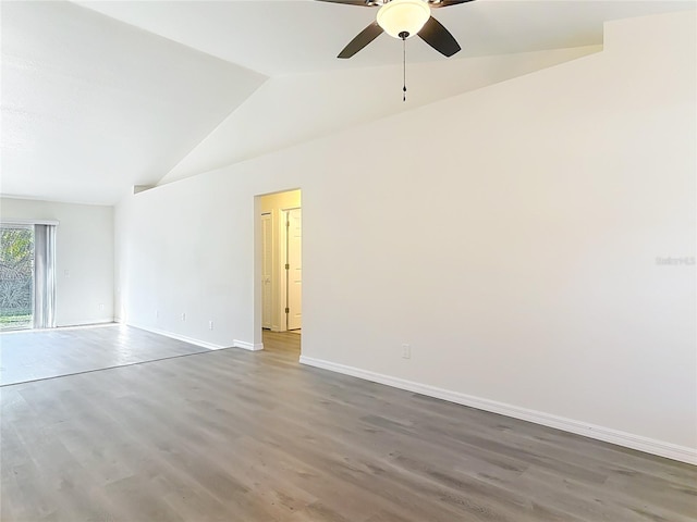 spare room with wood finished floors, a ceiling fan, baseboards, and vaulted ceiling