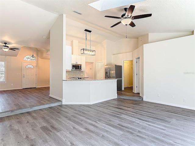 unfurnished living room featuring wood finished floors, baseboards, visible vents, a sink, and ceiling fan